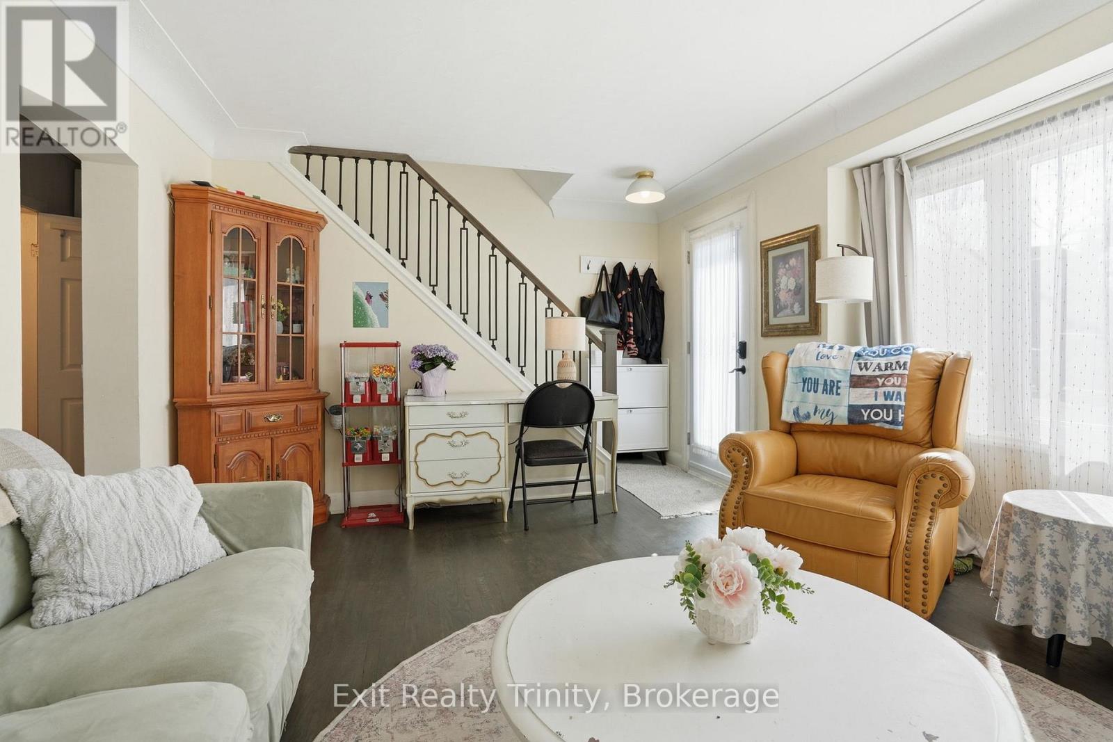 A living room with a couch, chair, and a table with a vase of flowers on it.