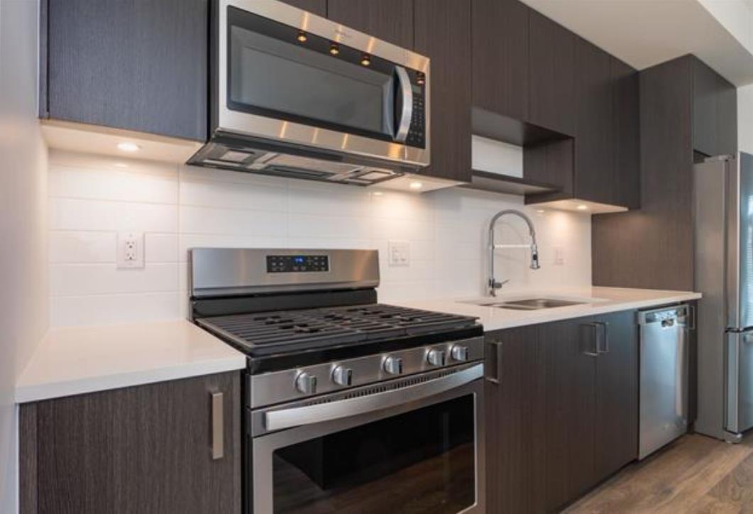 A modern kitchen with dark brown cabinets and stainless steel appliances.