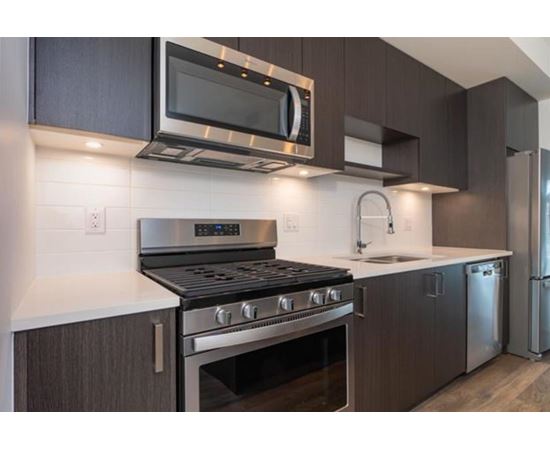 A modern kitchen with dark brown cabinets and stainless steel appliances.
