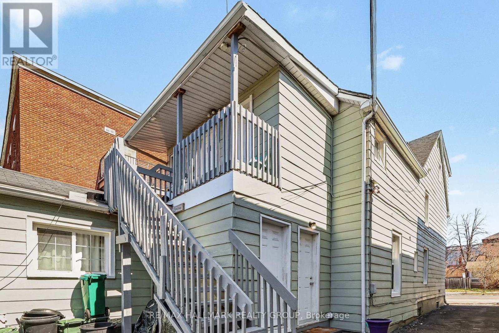 A house with a grey and white exterior and a metal staircase leading to the second floor.