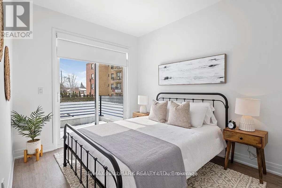 A bedroom with a large bed, a nightstand, and a window overlooking a cityscape.