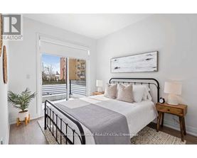 A bedroom with a large bed, a nightstand, and a window overlooking a cityscape.