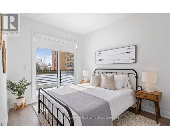 A bedroom with a large bed, a nightstand, and a window overlooking a cityscape.