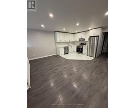 A spacious kitchen with wood flooring and stainless steel appliances.