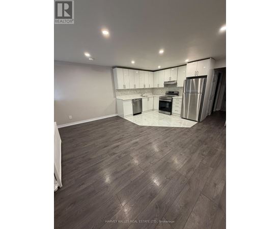 A spacious kitchen with wood flooring and stainless steel appliances.