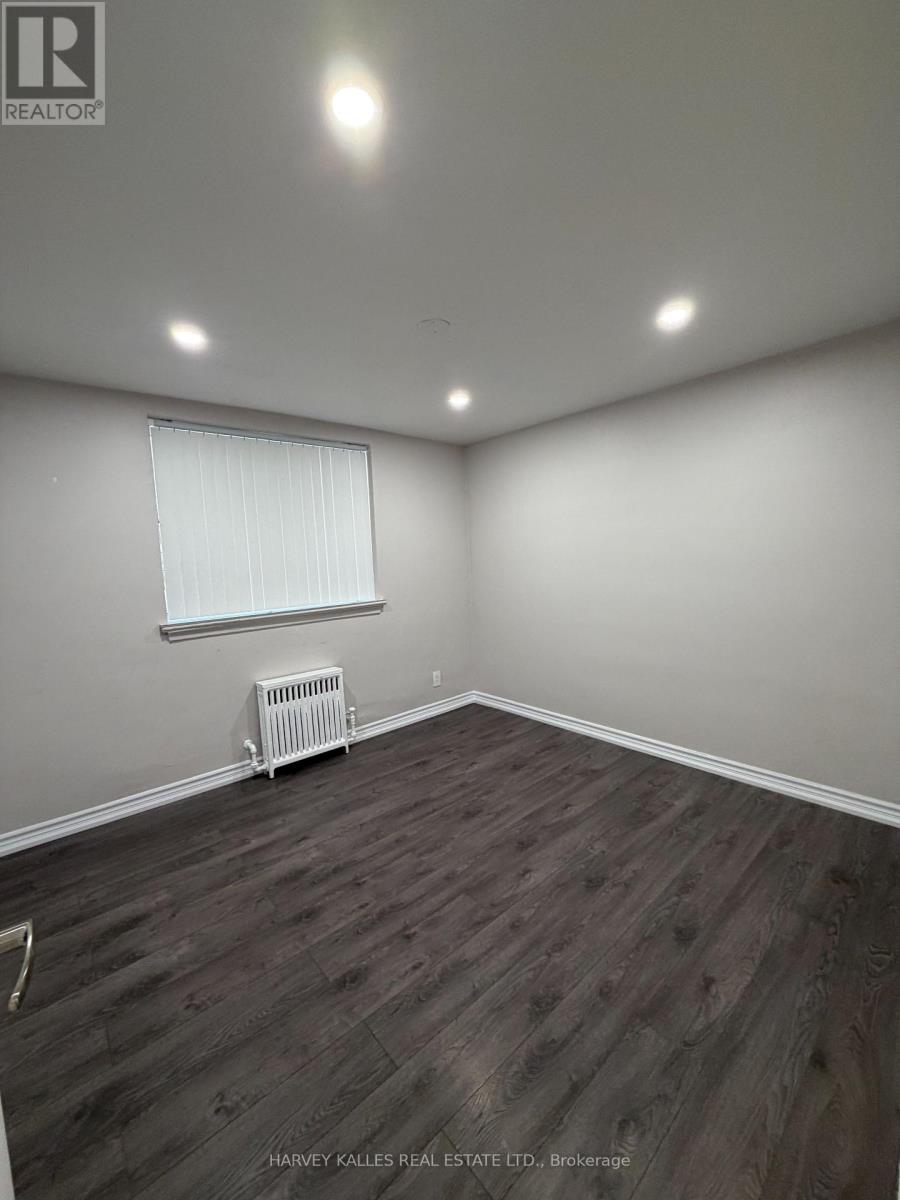 A room with wooden flooring and a window with blinds.