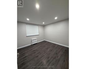 A room with wooden flooring and a window with blinds.