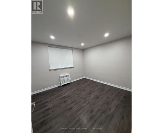 A room with wooden flooring and a window with blinds.