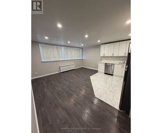 A spacious kitchen with white cabinets and a dark wood floor.