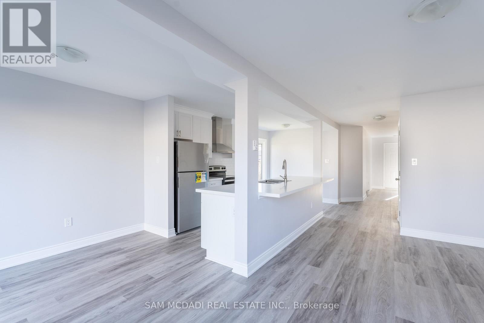 A spacious room with a kitchen area and a refrigerator.