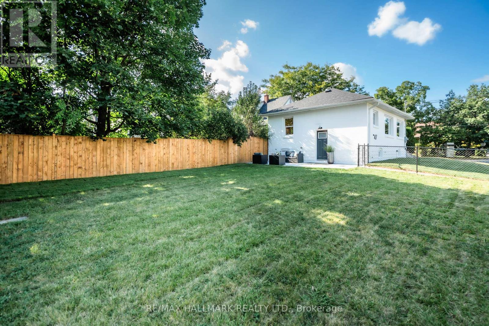 A white house with a brown fence and green grass in front.