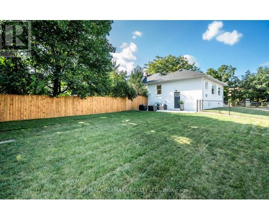 A white house with a brown fence and green grass in front.