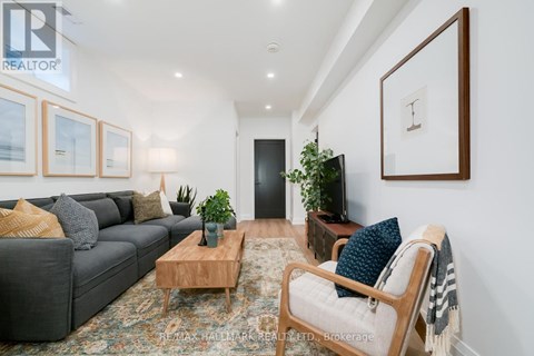 A living room with a grey couch, a wooden coffee table, and a large painting on the wall.