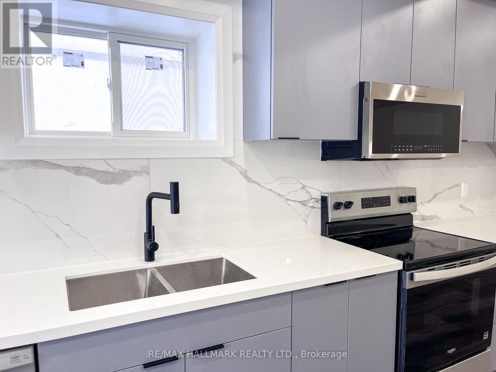 A modern kitchen with a sink, stove, and microwave.