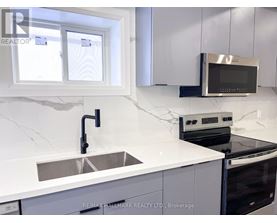 A modern kitchen with a sink, stove, and microwave.