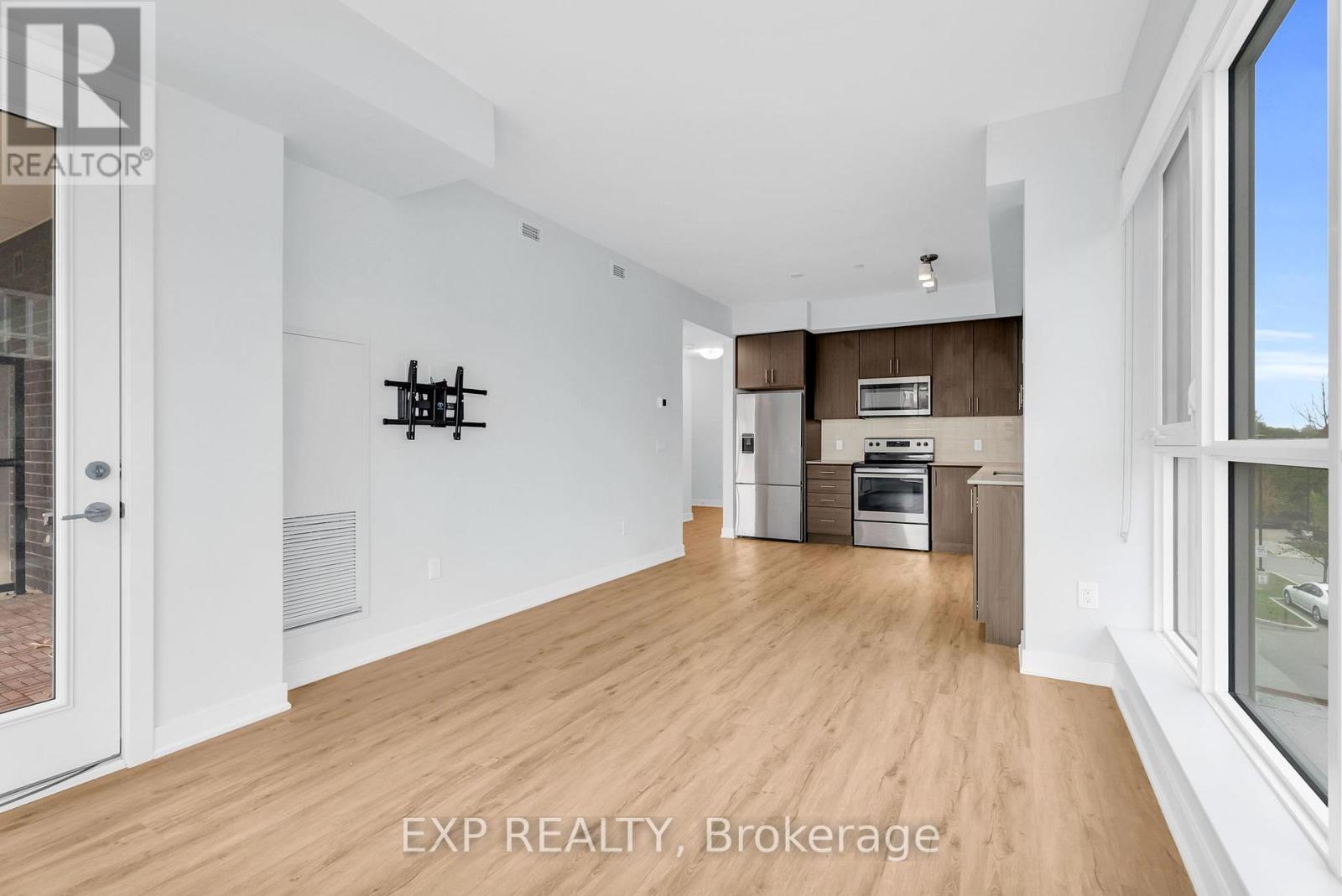 A spacious room with wooden flooring and a large window on the right side.