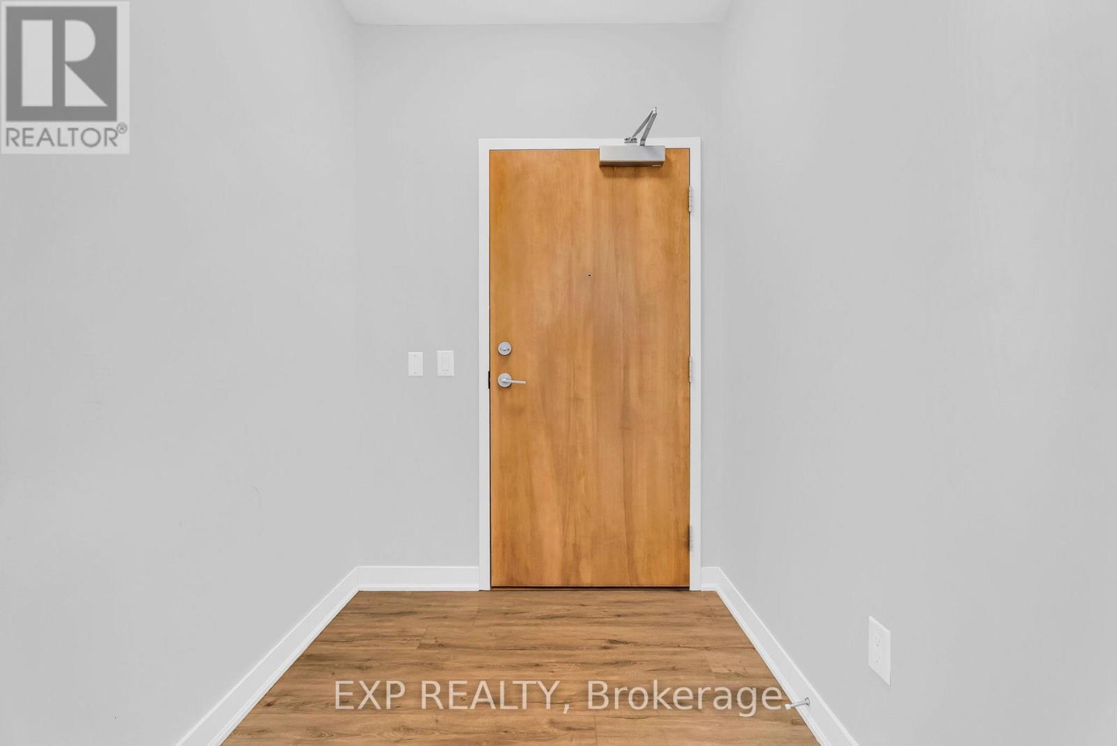 A room with a wooden door and EXP REALTY, Brokerage written on the floor.