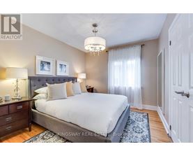A bedroom with a large bed, a chandelier, and a nightstand with a lamp.