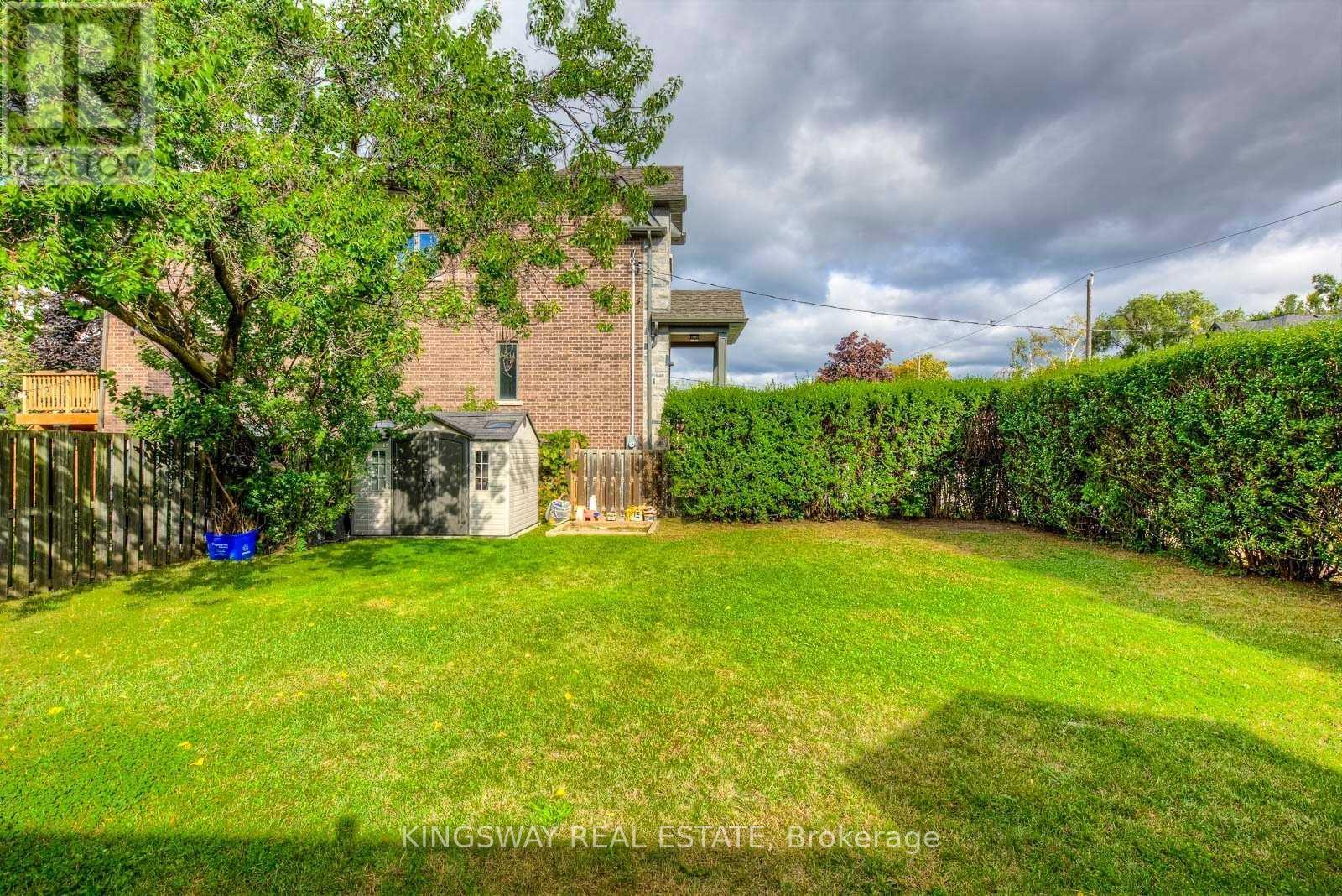 A backyard with a green lawn and a building in the background.