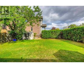 A backyard with a green lawn and a building in the background.