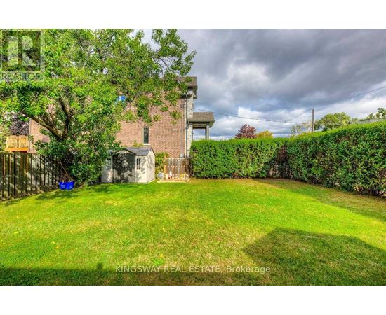 A backyard with a green lawn and a building in the background.