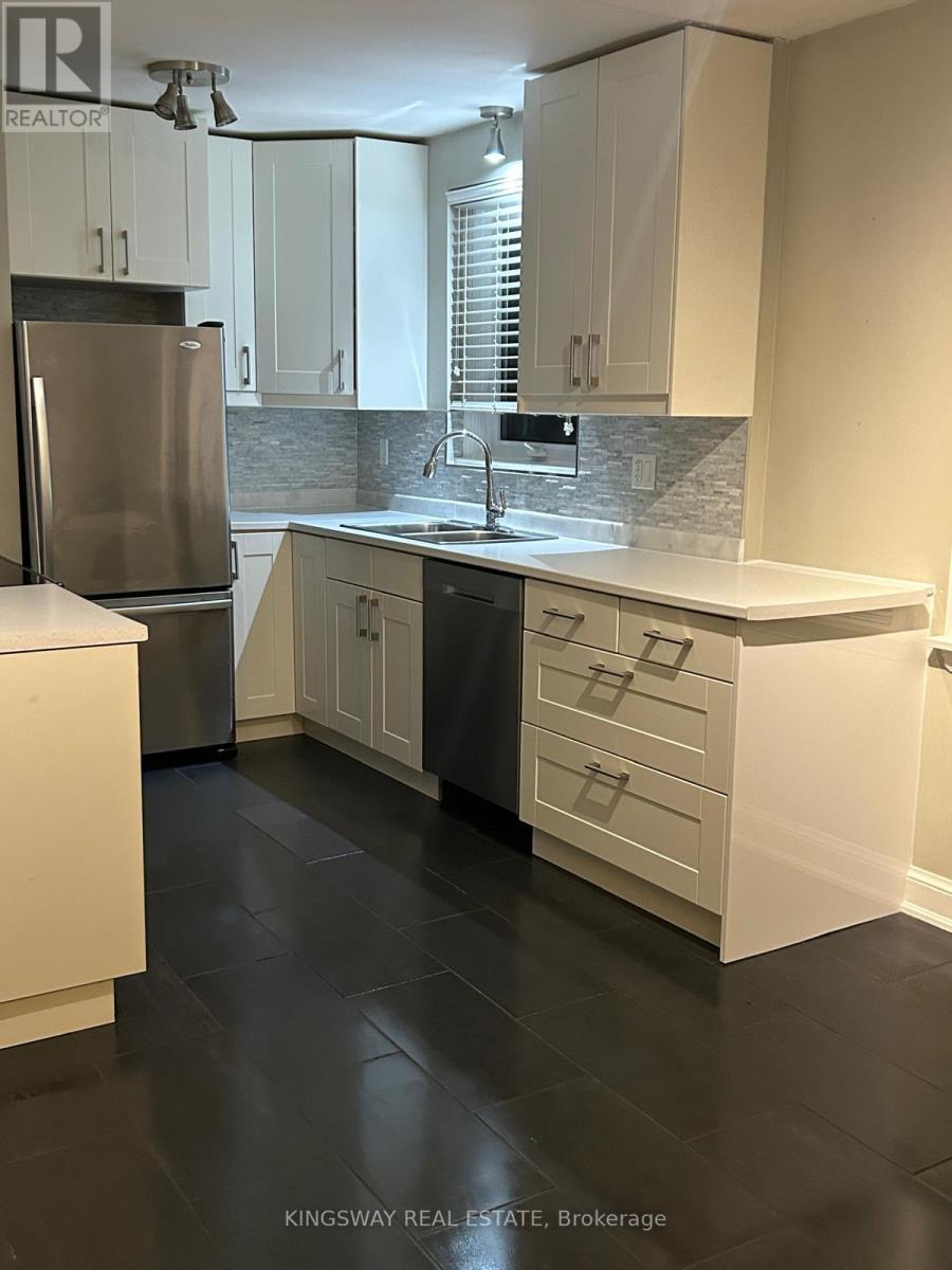 A kitchen with white cabinets and a stainless steel refrigerator.