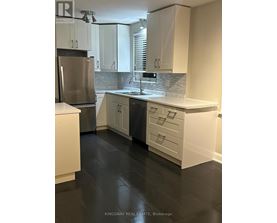 A kitchen with white cabinets and a stainless steel refrigerator.