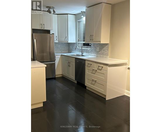 A kitchen with white cabinets and a stainless steel refrigerator.
