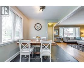 A dining room with a table set for two and a couch in the background.