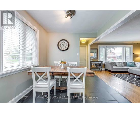 A dining room with a table set for two and a couch in the background.