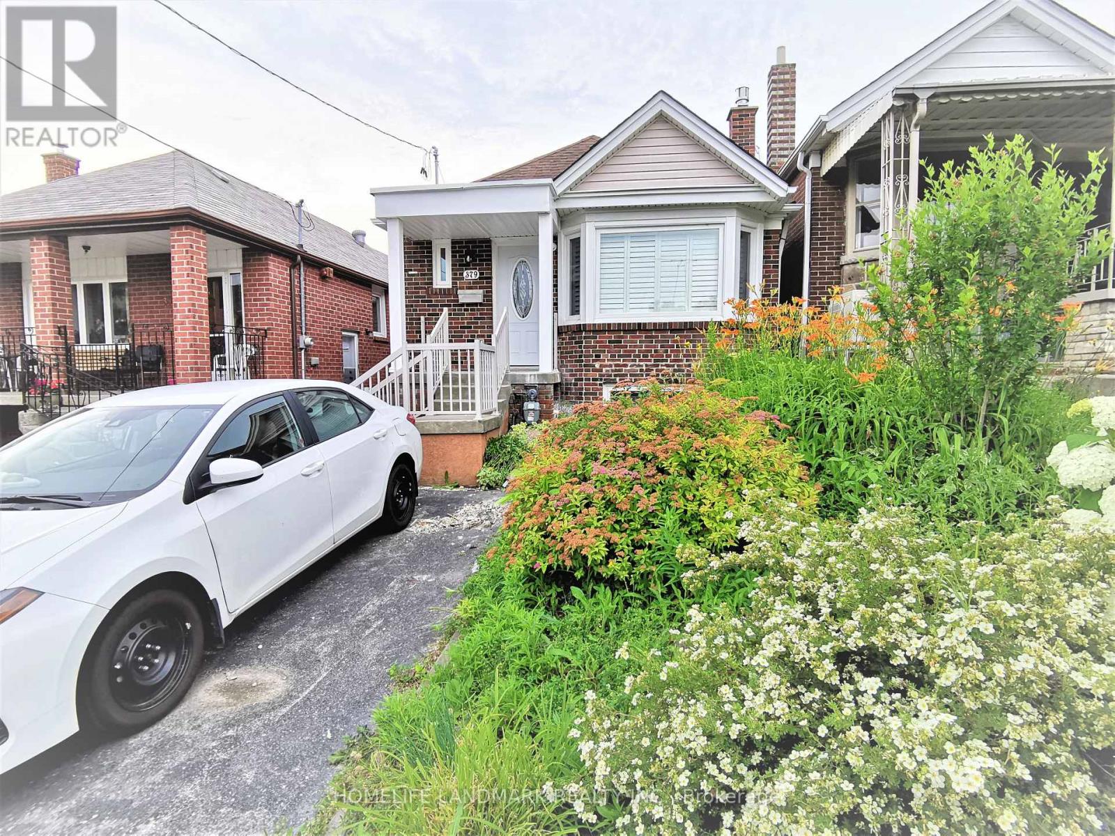 A white car is parked in front of a house.