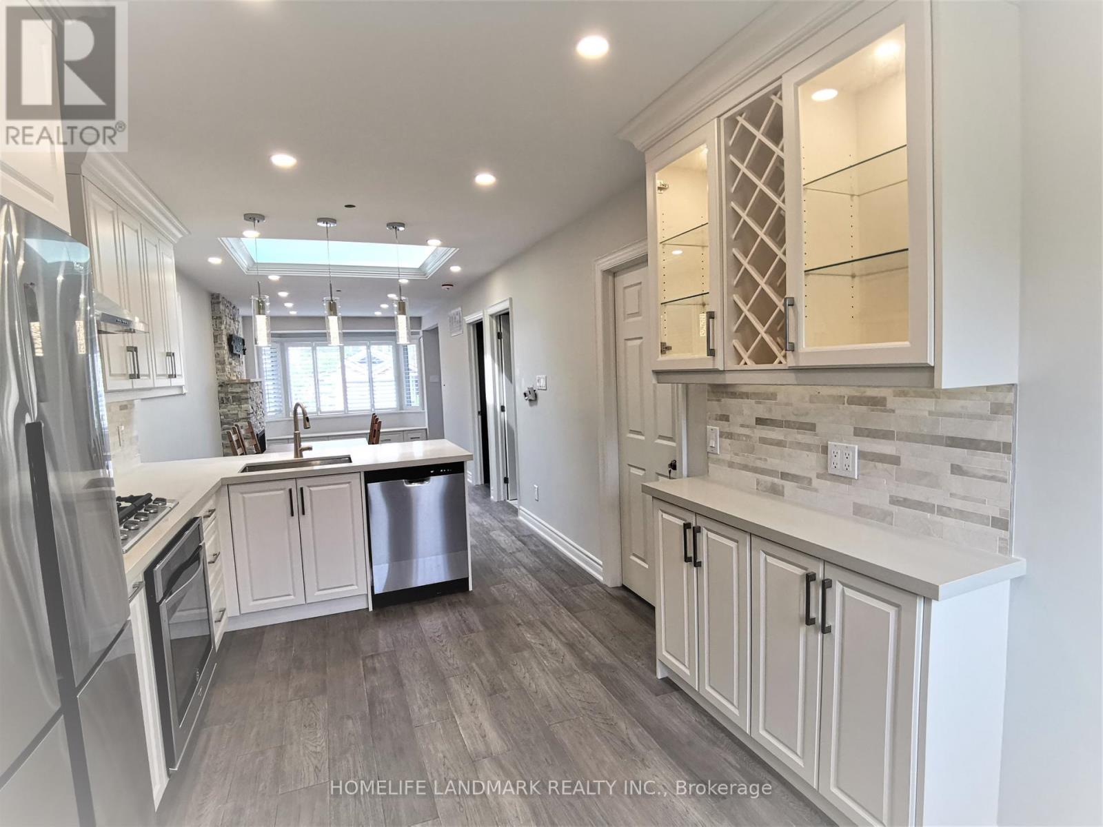 A well-lit, modern kitchen with a refrigerator, stove, and cabinets.
