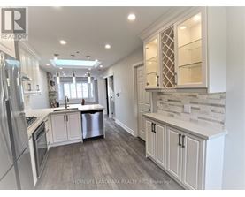 A well-lit, modern kitchen with a refrigerator, stove, and cabinets.