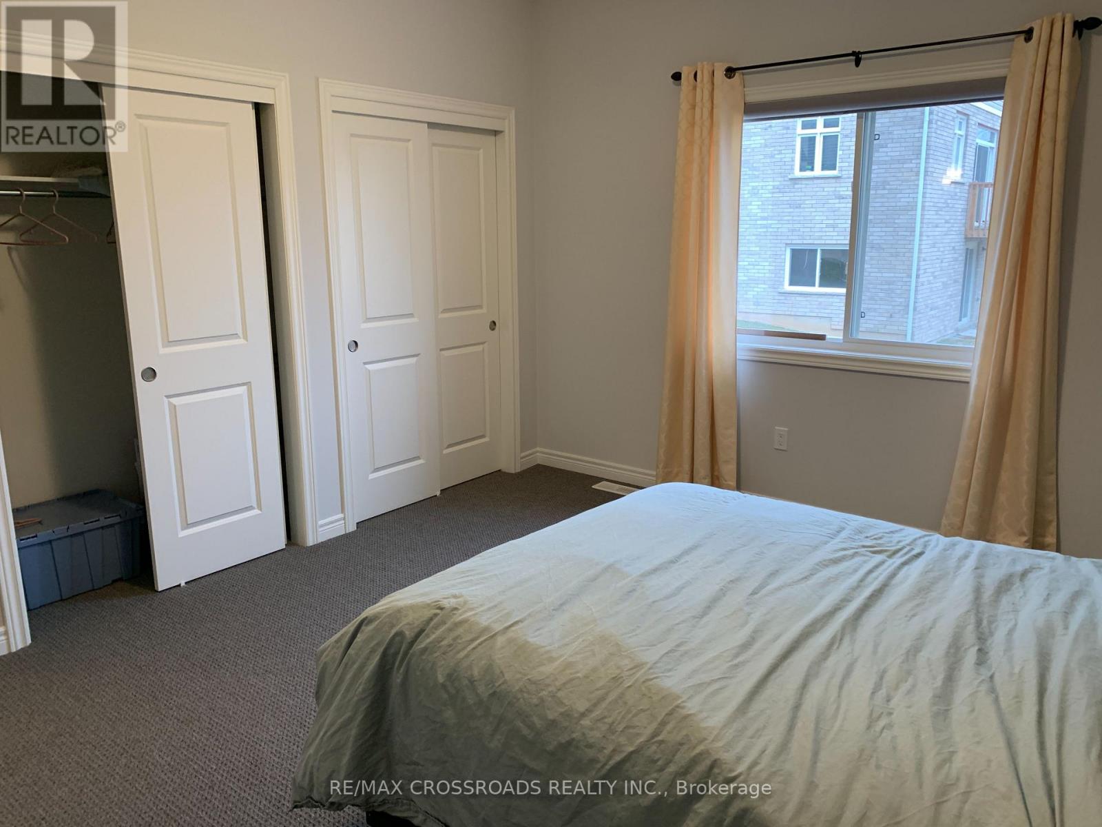 A bedroom with a bed, two doors, and a window with curtains.