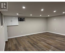 A room with wooden flooring and white walls, with a window and a cabinet.