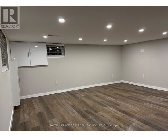 A room with wooden flooring and white walls, with a window and a cabinet.