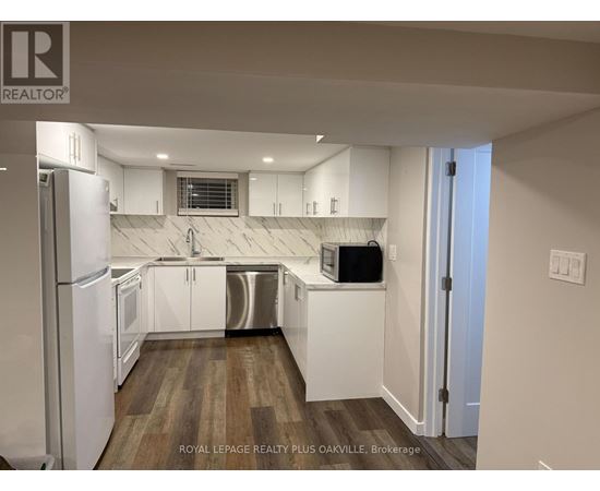 A kitchen with white cabinets and a refrigerator.
