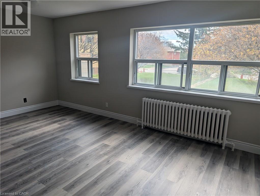 A room with a grey wall and a window with a view of a tree-lined street.