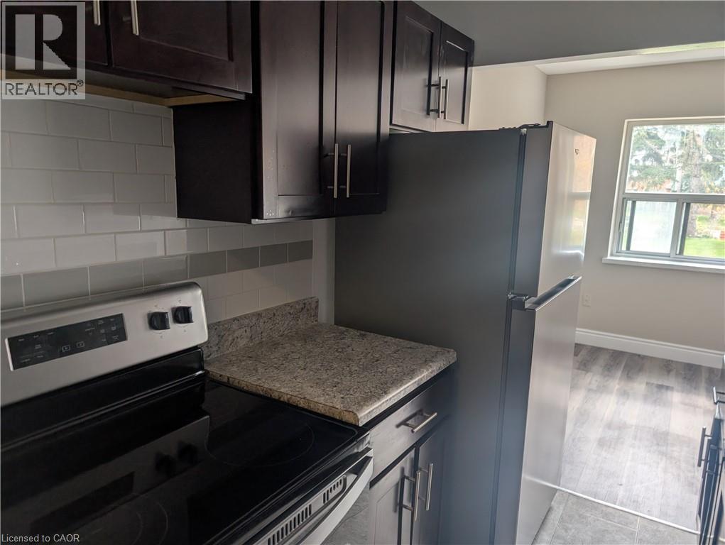 A kitchen with a black refrigerator and stove top oven.