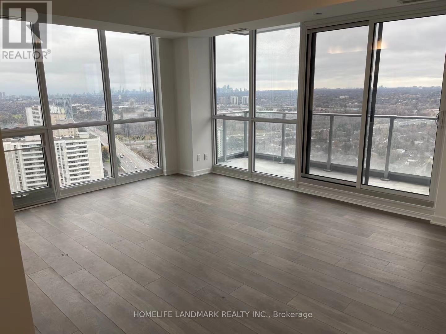 A large, empty room with a view of the cityscape outside the windows.
