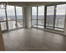 A large, empty room with a view of the cityscape outside the windows.