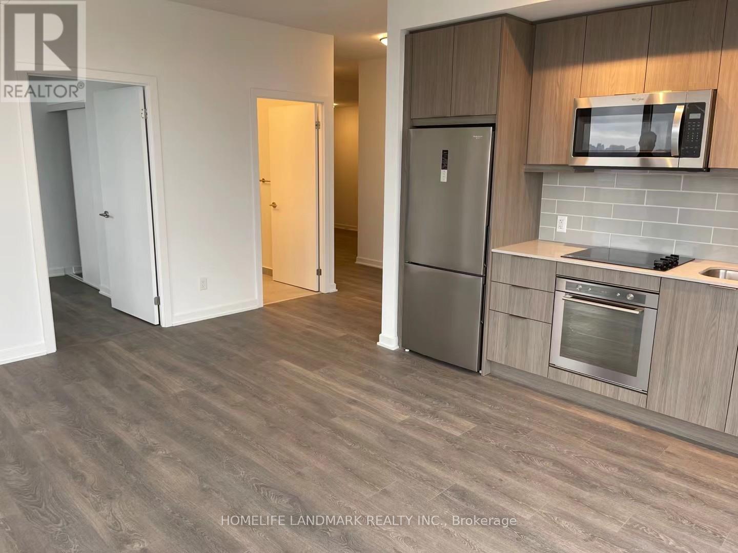 A kitchen with a refrigerator, oven, and microwave.