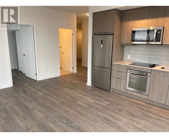 A kitchen with a refrigerator, oven, and microwave.