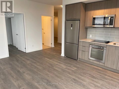 A kitchen with a refrigerator, oven, and microwave.