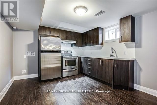 A modern kitchen with dark wood floors and stainless steel appliances.