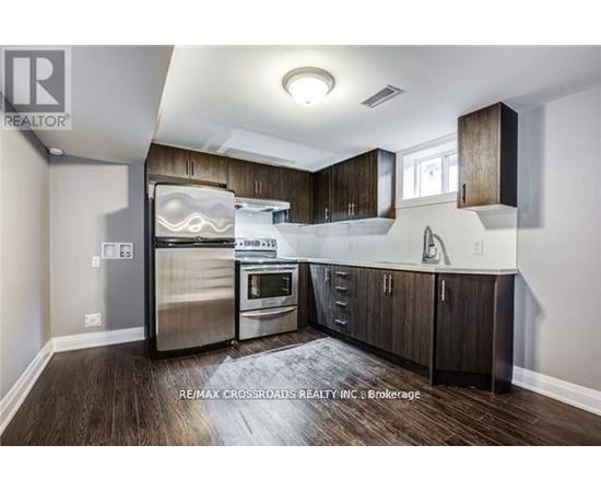 A modern kitchen with dark wood floors and stainless steel appliances.