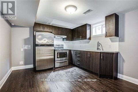 A modern kitchen with dark wood floors and stainless steel appliances.