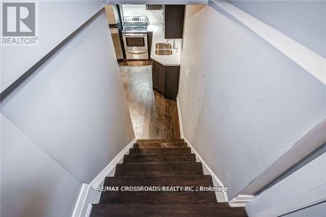 A staircase with a wooden handrail leads to a kitchen area.
