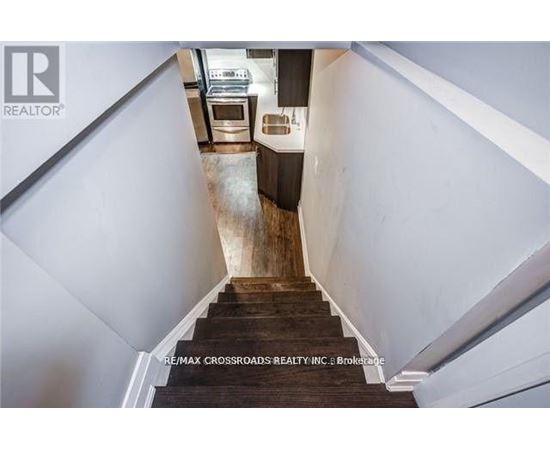 A staircase with a wooden handrail leads to a kitchen area.