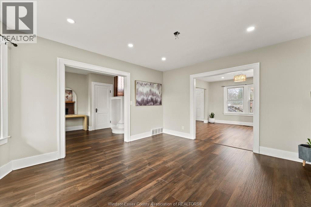 A spacious room with wooden flooring and white walls.
